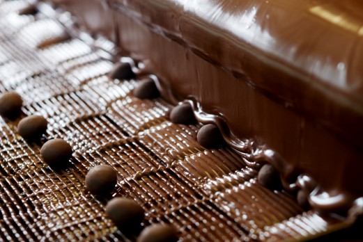 Covering chocolate macadamias with premium chocolate and decorative swirl.